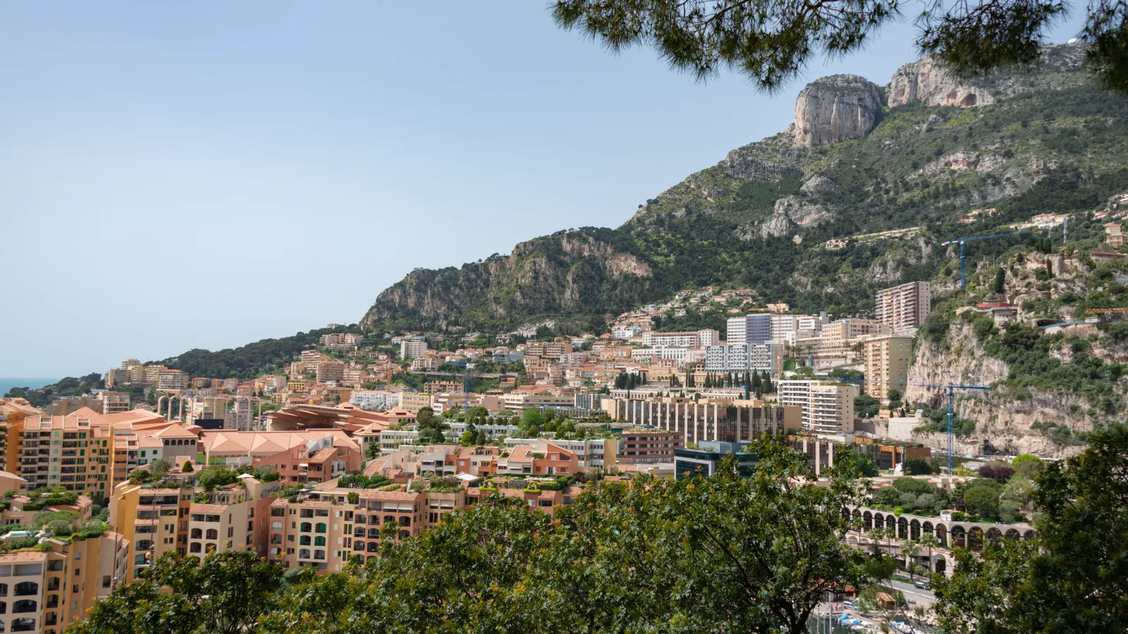 Aerial view of Port Hercule and the districts of Monaco rising behind it on a clear working day.