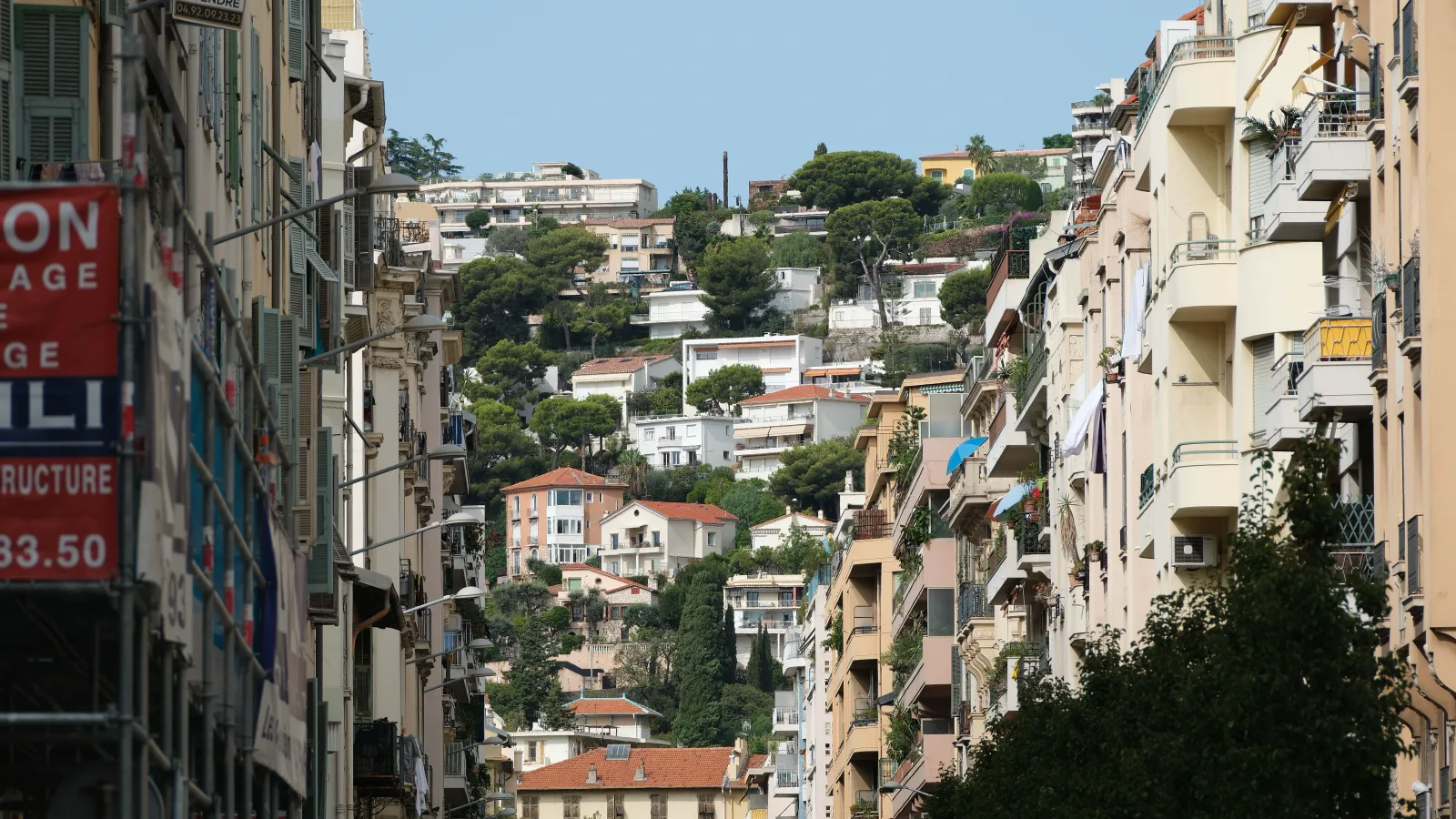 Residential apartment blocks rising on the hillside above the port of Monaco, photographed in daylight.