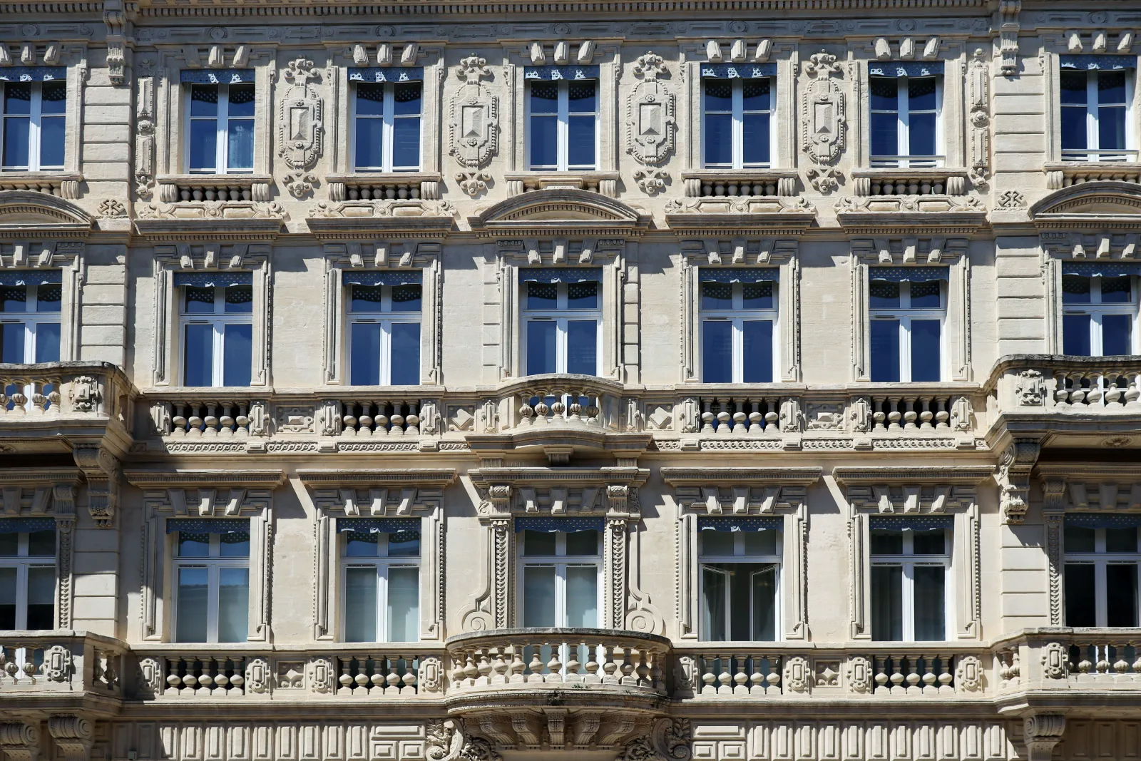 Stone facade of an office building with shuttered windows in daylight