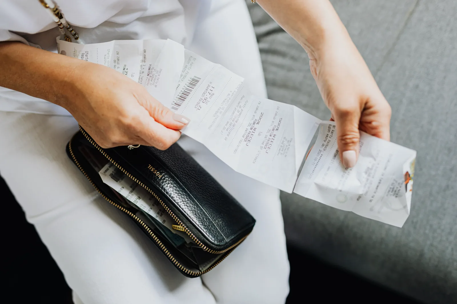 A paper sales slip handed across a shop counter, hands and receipt in focus